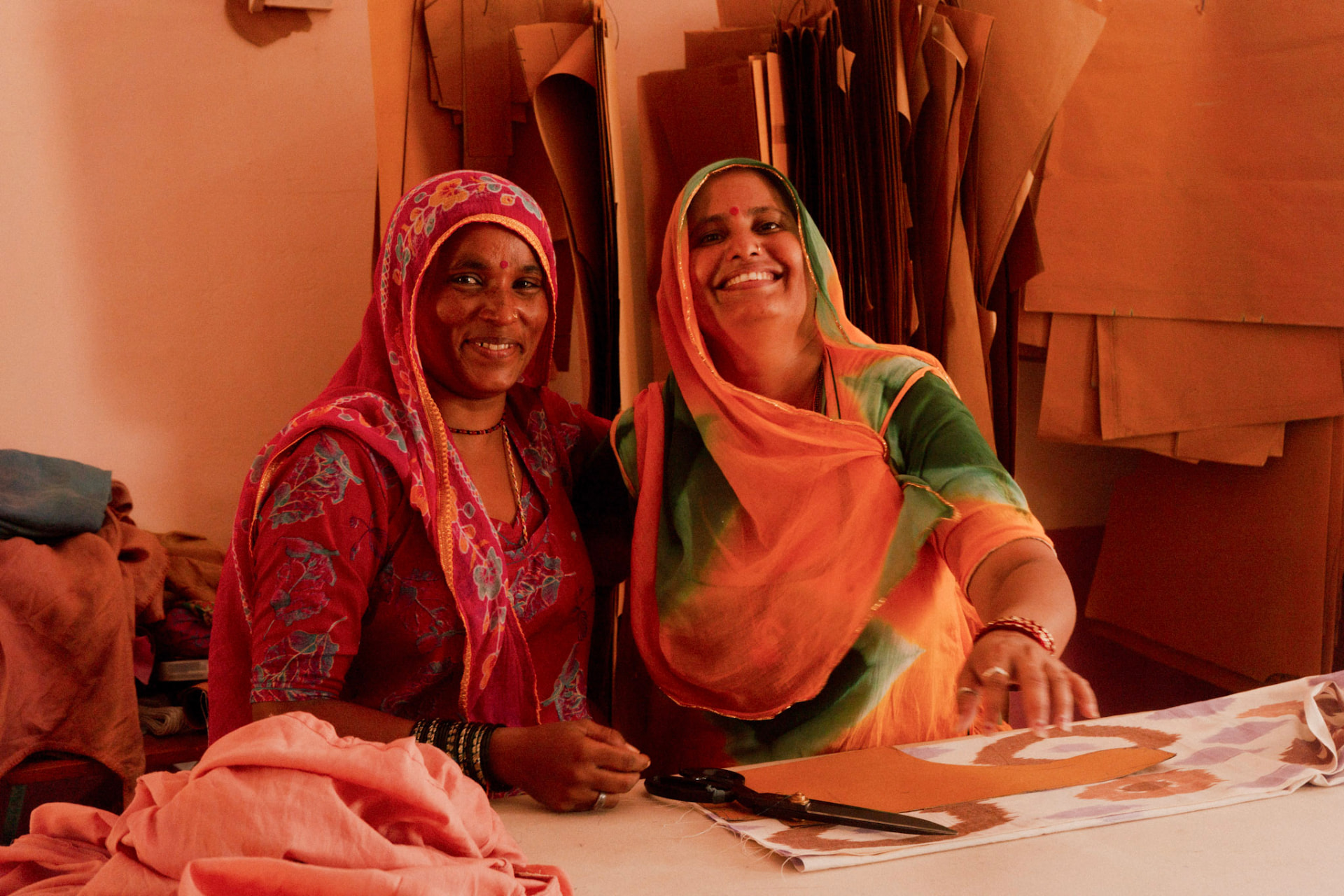 Two Saheli women smiling at the cutting table