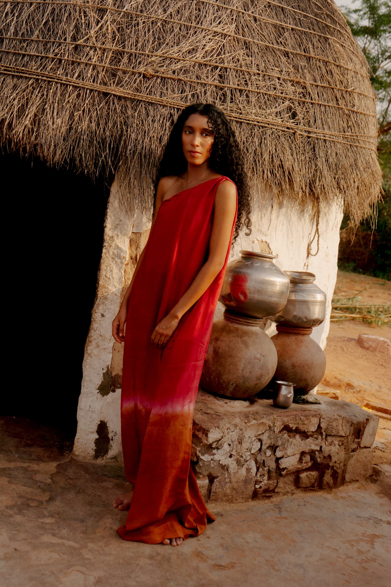 Hand-dyed red silk dress beside a thatched hut
