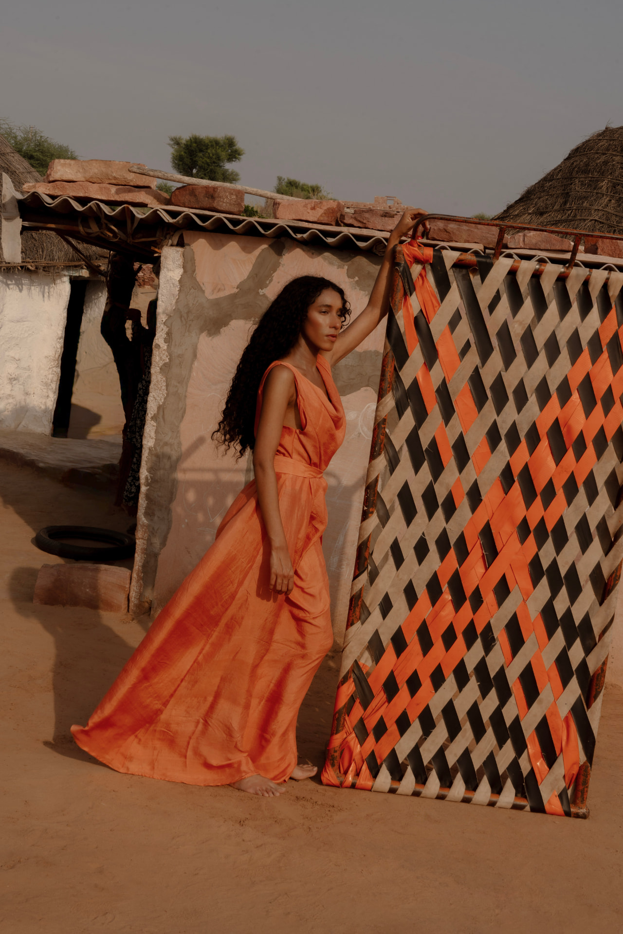 Hera dress in terracotta mulberry silk beside a woven screen