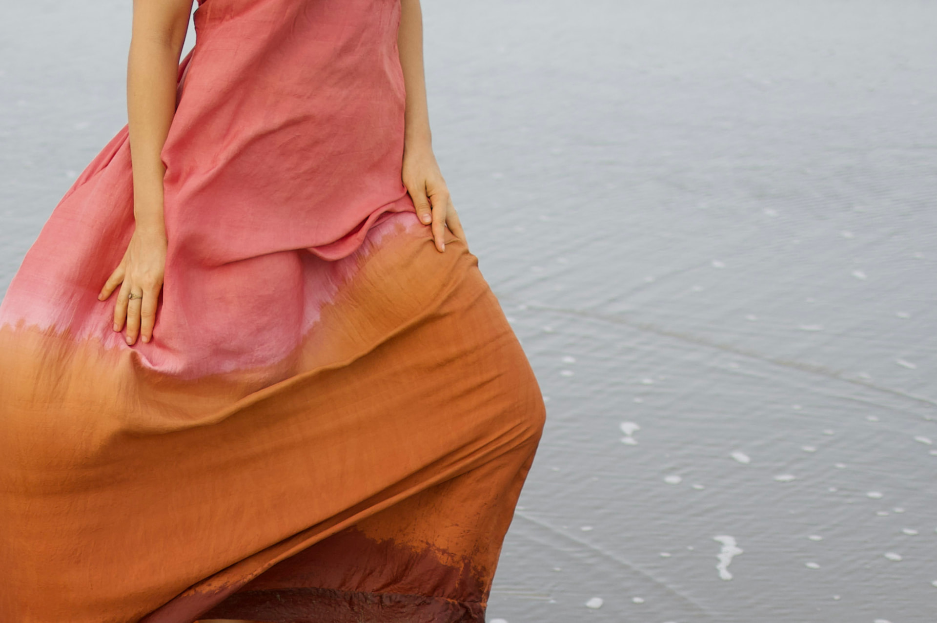 Detail of hand-dyed pink and rust ombre mulberry silk skirt at the water's edge