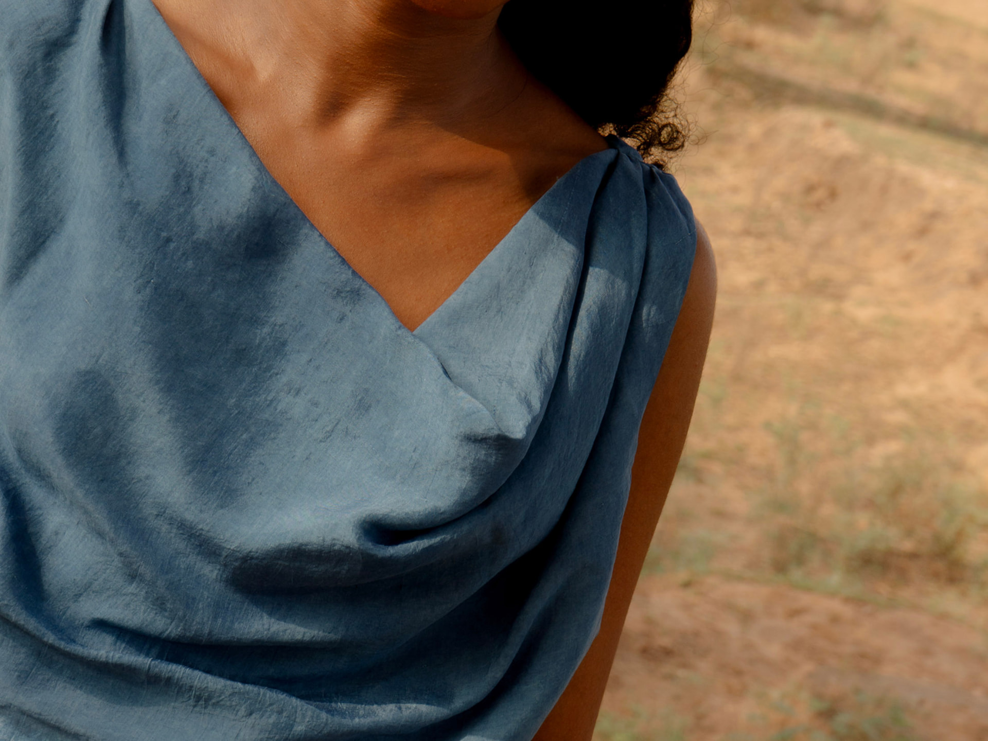 Detail of the indigo blue draped neckline of the Hera dress