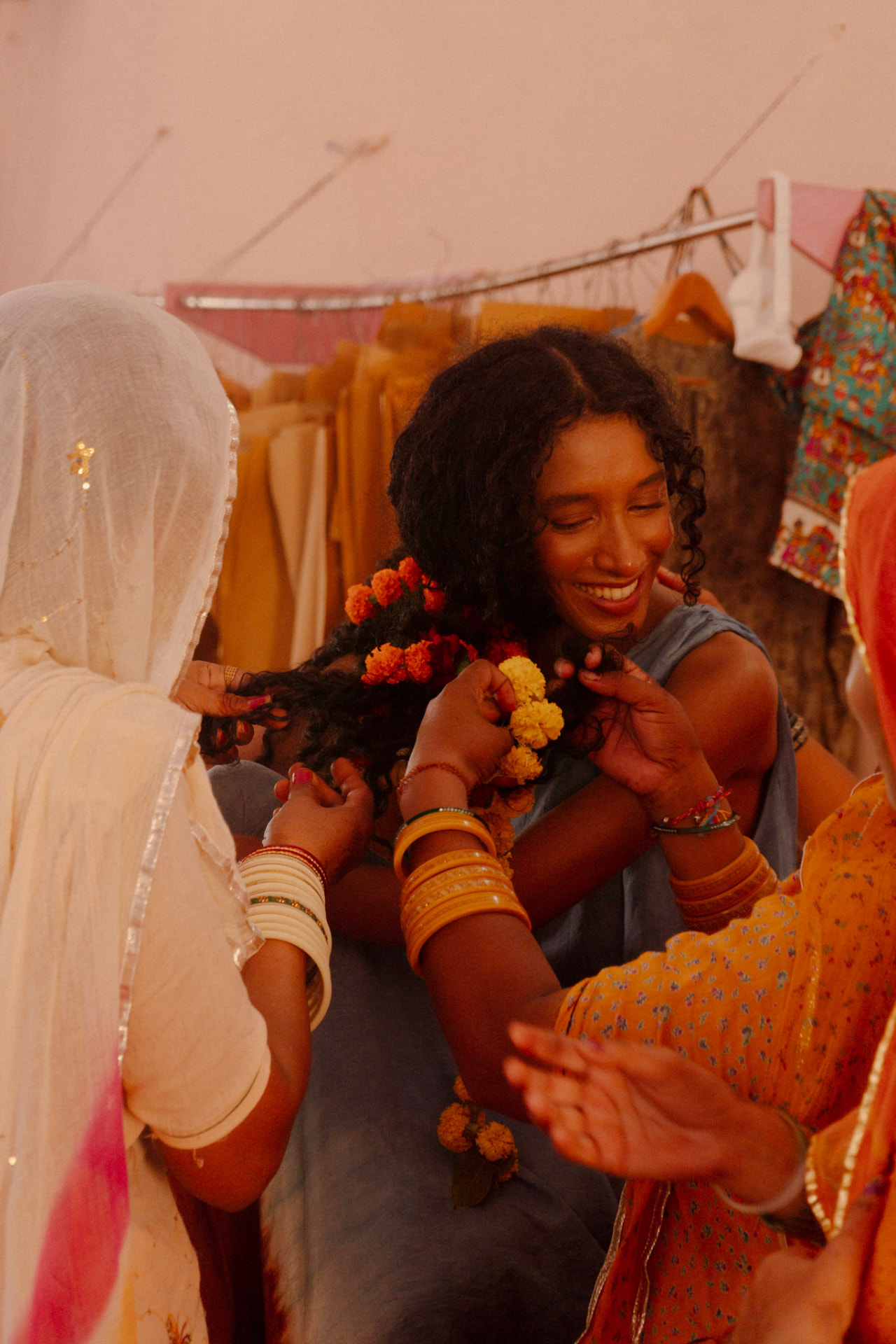 Women at the Saheli centre braiding marigolds into a model's hair
